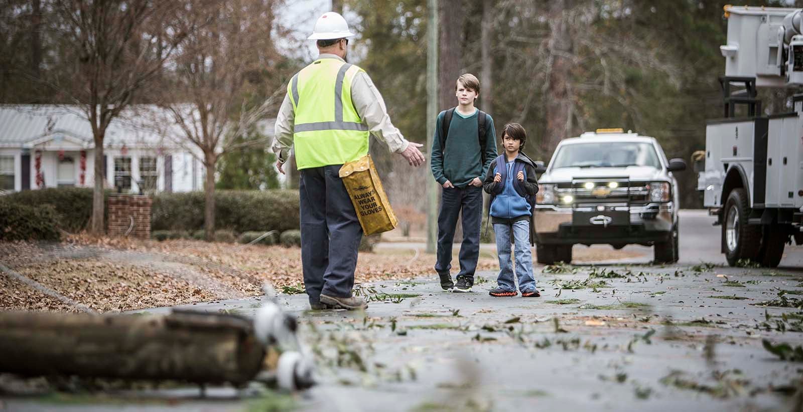Worker keeping kids away from downed power line