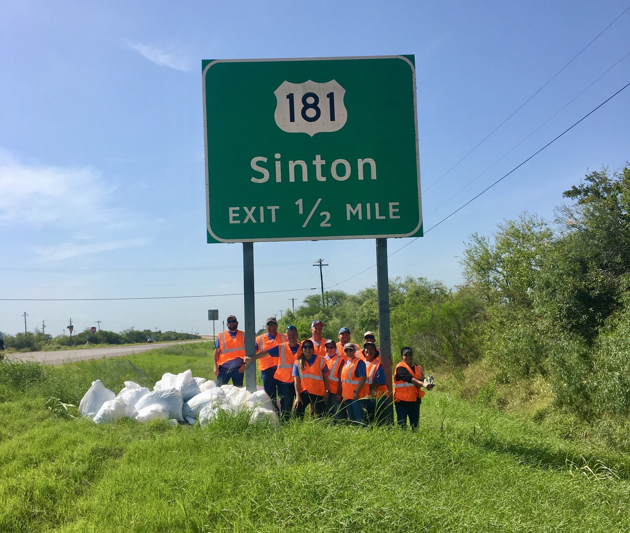 SPEC Employees posing next to sign and trash collected at Adopt-A-Highway